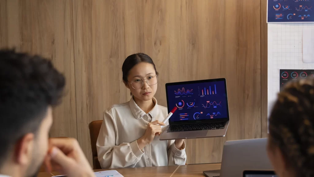 Office workers analyzing data analytics screens on a computer.