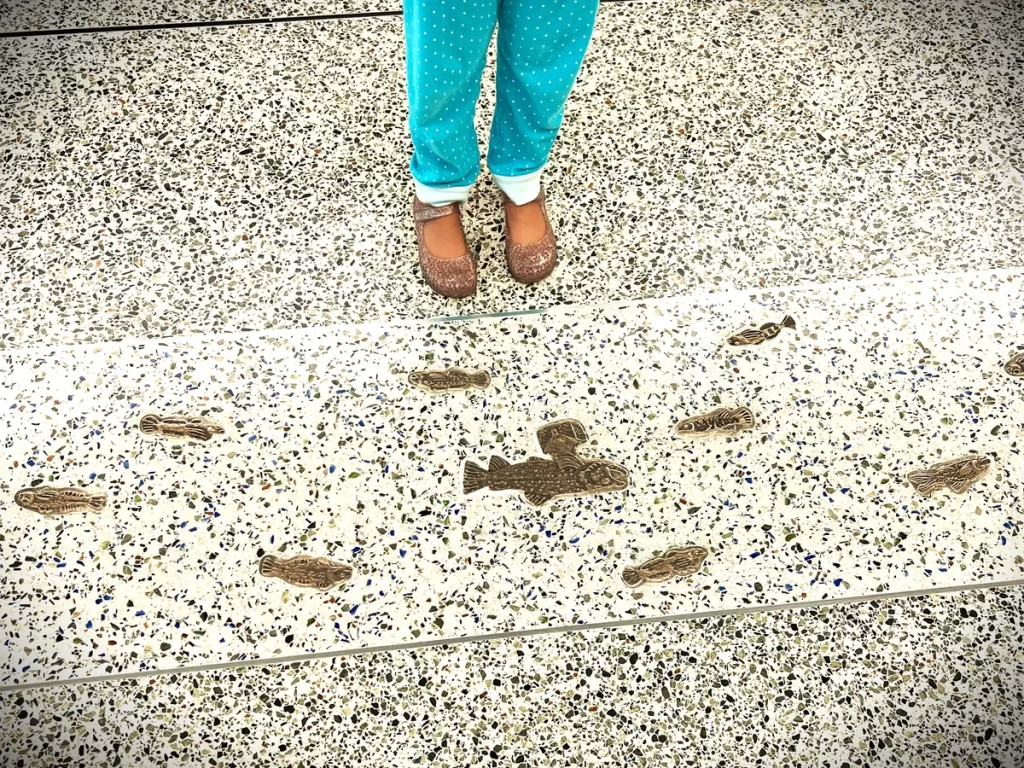 My daughter in front of the fish on the floor of Seattle airport