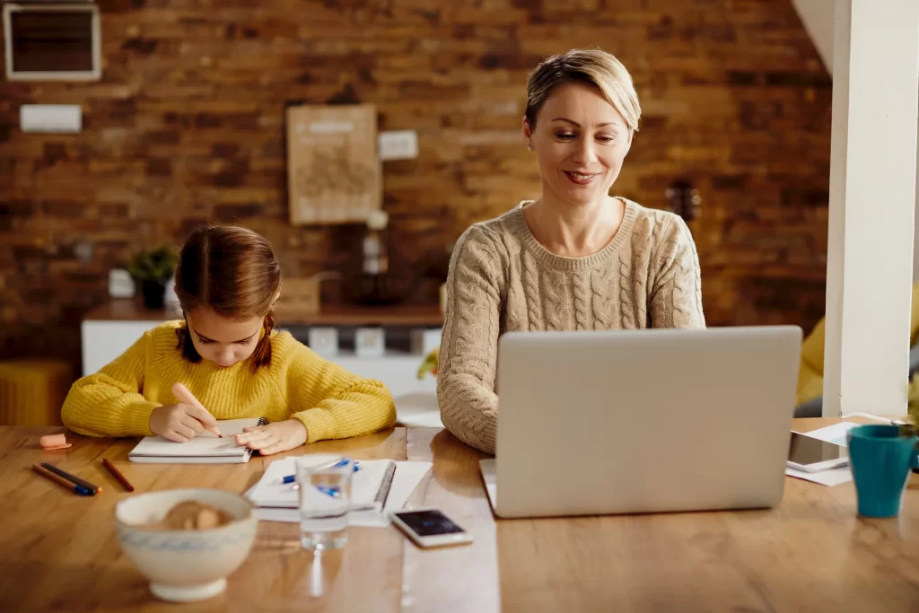 Remove worker working on her computer with her daughter next to her