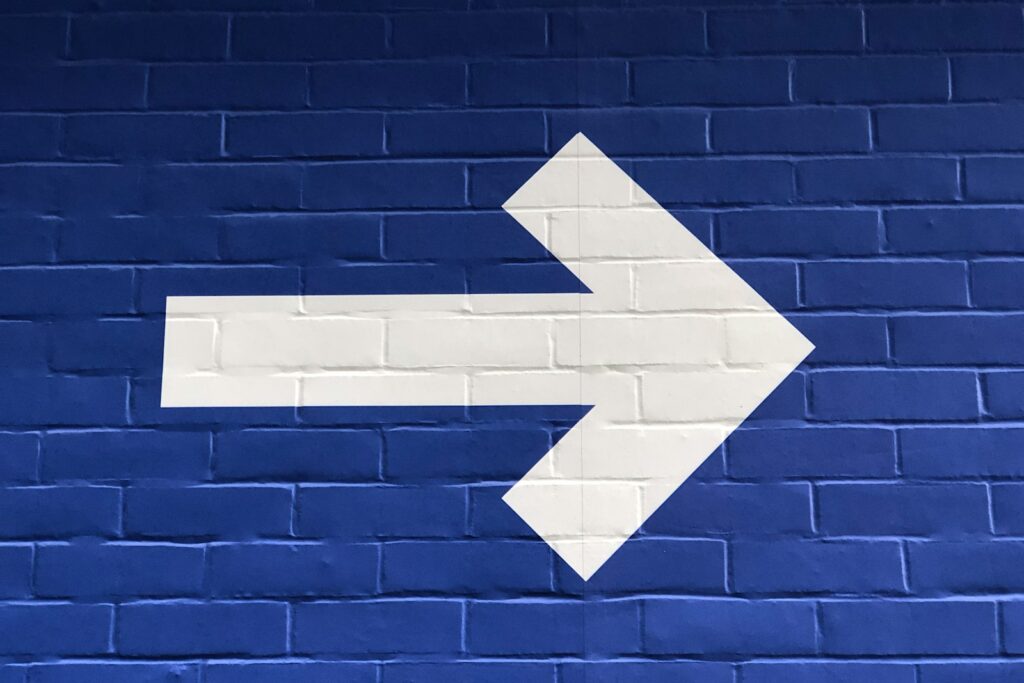 White arrow painted on brick wall signifying moving forward